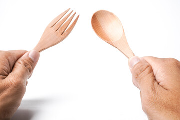 Close-up photo of Someone hand is holding wooden table spoon and fork isolated on white background.