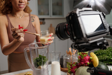 Close-up of cameraman shooting model on camera while she cooking cocktail
