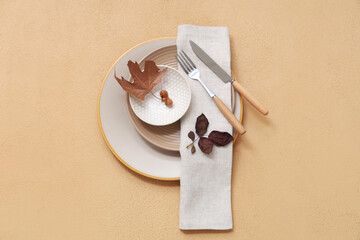 Beautiful table setting with autumn leaves on beige background