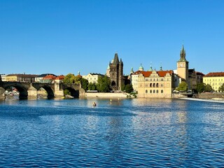 Fototapeta premium The photo captures a landscape of Prague featuring the river and its historic buildings.