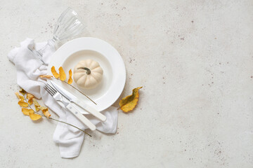 Beautiful table setting with fresh pumpkin and autumn leaves on white background
