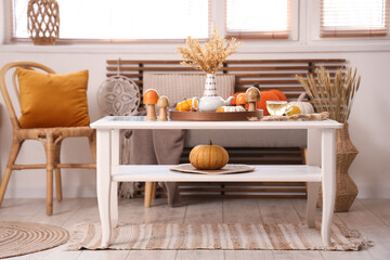 Coffee table with teapot, cup of green tea and autumn decor in interior of living room