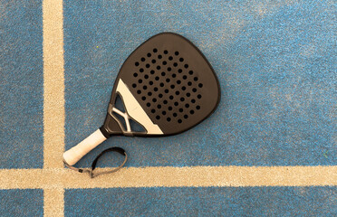 view from above of a green paddle racket and a ball on a blue synthetic paddle tennis court 
