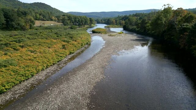 Drone descends along shallow river water of Mohawk Trail by Deerfield River in Western Massachusetts New England USA