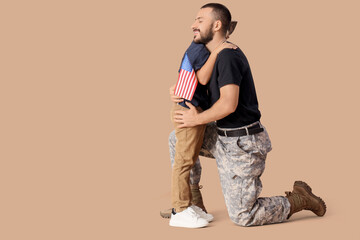 Fototapeta premium Little boy hugging his military father with USA flag on beige background. Veterans Day celebration