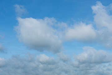 Fluffy cumulus clouds drift across a bright blue sky, painting a beautiful summer landscape