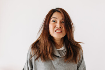 Obraz premium Funny angry asian Thai woman wear sweater, going crazy mad, hand gesture, isolated over white background wall.