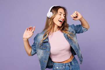 Young woman she wear denim jacket violet top casual clothes listen to music in headphones sing song...