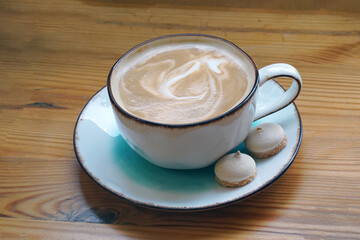 Cup of coffee with two biscuits on a wooden table