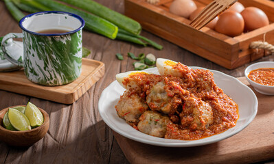 A plate of traditional siomai, a type of Indonesian steamed dumpling served with a spicy peanut sauce and accompanied by hard-boiled eggs. a hand holding a fork is lifting a piece
