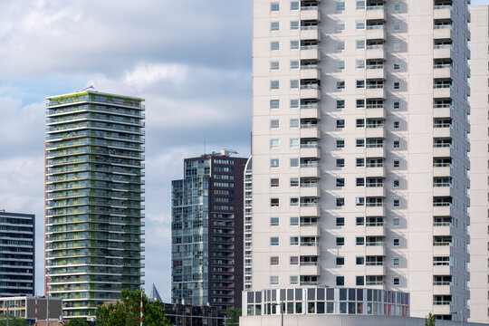 This image captures a modern urban landscape with various tall residential and office buildings against a partially cloudy sky, highlighting urban architecture.