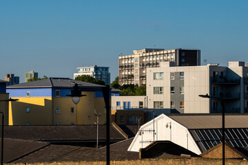 A vibrant scene of diverse architectural styles, highlighting colorful residential units juxtaposed with modern buildings, creating a relaxed urban neighborhood atmosphere in London UK