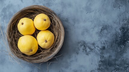 Four yellow pears in a wooden bowl with hay, on a gray background.