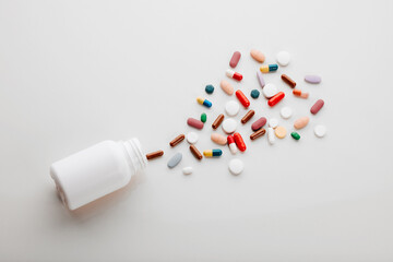 Pills, above and healthcare in studio, medicine and supplements with vitamins, medical and clinic. White background, pouring and top view of container, pharmaceutical and painkillers in mockup space