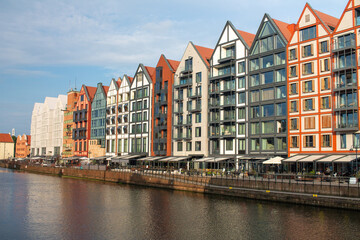 Modern buildings along the waterfront in Gdańsk, with visible apartments, hotels, and restaurants by the riverside. © brahol9