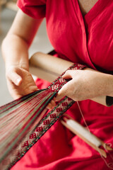a craftswoman weaves a belt