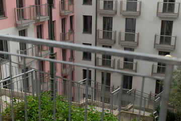 A balcony adorned with a protective fence and an expansive view of an urban building nearby, offering glimpses of the cityscape