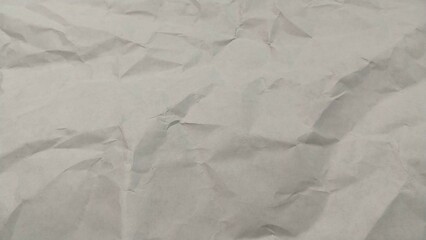 a piece of crumpled paper. The paper appears to be light gray or off-white in color, and the crumples create a textured pattern across its surface. There are no distinct markings or text visible