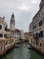 Tower, old buildings, canal and boats in Venice, Italy.