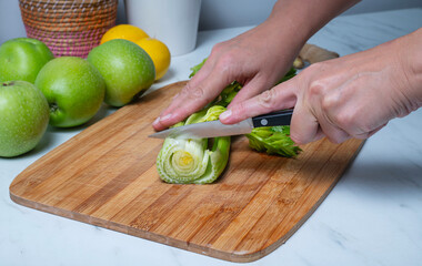 Cutting fresh celery stalks on a wooden board. detox concept and healthy food