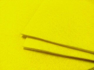 a close-up of a bright yellow surface with two thin, elongated objects lying on it. The objects appear to be slightly raised from the surface, casting shadows.