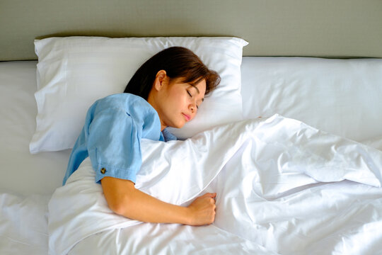 Woman lying in bed on her side with a hand under the pillow