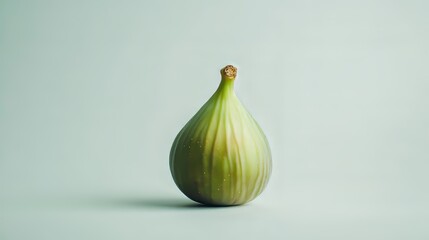Fototapeta premium A single green fig, perfectly ripe, sits on a plain white background.