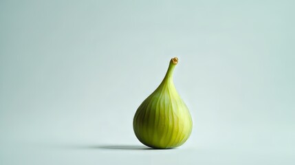 Fototapeta premium A single green fig, perfectly ripe, sits on a plain white background.