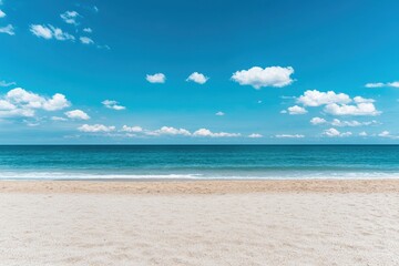 Obraz premium Pristine beach with soft sand and clear ocean under a bright blue sky with scattered clouds