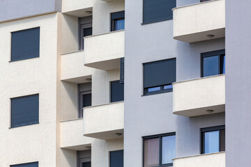 Close-up of a modern building facade with curved balconies and windows, featuring a minimalistic design in neutral colors