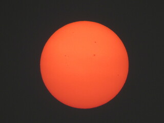 Photo of the sun on a day with a lot of smoke from the fires during the prolonged dry season. Photo of the reddish sun with details of sunspots