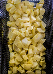 Basket of dices potatoes in the deep fryer