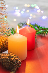 Christmas decoration with candles and pine cone on a red background with bokeh