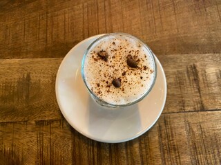 Top view of a cappuccino with foam and coffee beans on a wooden table