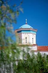 Beautiful church dome with a blue roof and cross, surrounded by greenery