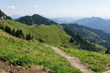 Lush green mountain landscape with path and distant peaks.