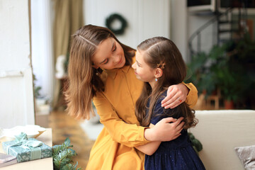 two sisters are joyfully embracing each other on Christmas Eve, radiating warmth and love. They are...