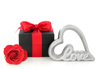Valentines Day rose flower, gift box with red bow and silver love sign on white background. Romantic loving concept for a Valentine card, anniversary or birthday.