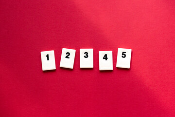 white chips with numbers 1, 2, 3, 4, 5 in ascending order on red background