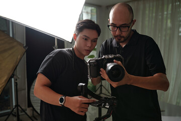 Cameraman setting his camera with assistant before shooting in studio