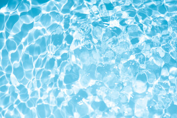 Blue water with ripples on the surface. Defocus blurred transparent blue colored clear calm water surface texture with splashes and bubbles. Water waves with shining pattern texture background.