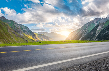 Asphalt highway road and green mountain nature landscape at sunset. Road trip.