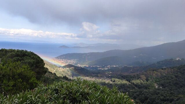 Rainbow over Elba Island Italy mist-covered sea mountains ancient Livorno village nestled in greenery. Misty atmosphere after rain scenic tropical mountainous views tropical landscape cloudy day
