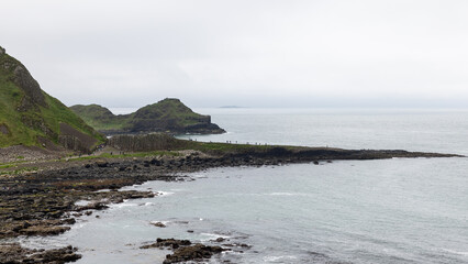 Panoramic view of Giant Causeway in Northern Ireland. Tourists walk along the famous basalt columns...