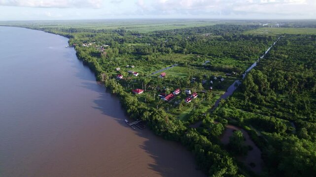 Drone flyover Frederiksdorp over large Commewijne river, Suriname rainforest