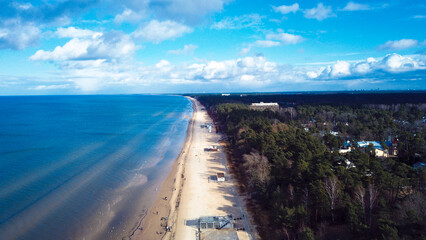 Fototapeta premium Breathtaking aerial view of Jurmala's coastline showcasing golden sands and lush greenery under a vibrant blue sky in late afternoon light