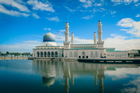 Majestic view of the Kota Kinabalu City Mosque reflected on calm waters during a clear day