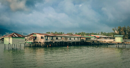 Traditional stilt houses along the waterfront in Kota Kinabalu under a cloudy sky during the...