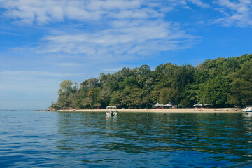 Clear waters of Mamutik Island reveal a serene beach surrounded by lush greenery and inviting skies in Malaysia