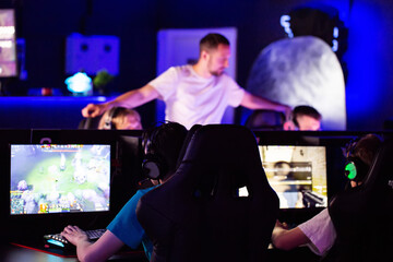 E-sport coach is watching trainer comments gives instructions to his players. Gamers in headset play video game on PC at computer club in tournament cyber sport team. Tactics strategy emotions Closeup © HENADZY